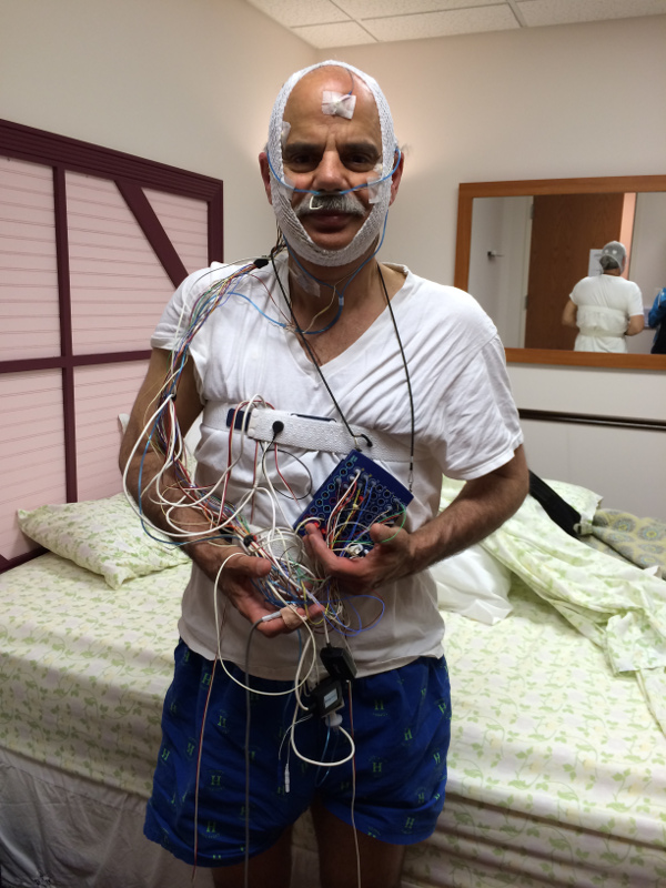 Our writer holds wires connected to him during his sleep study.